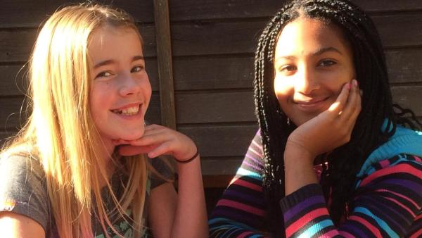 Pauline sitzt mit ihrer Freundin Angélique an einem Gartentisch in der Sonne. Beide lachen in die Kamera. | Rechte: ZDF