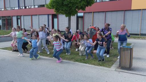 Die TanzAlarm Crew tanzt vor dem Schulgebäude zu AEIOU.