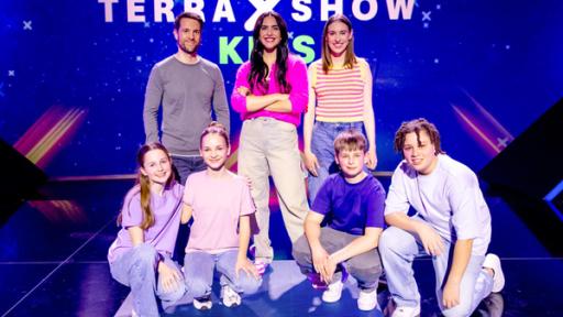 "Terra X"-Show Kids: Die Rateteams sitzen in der Hocke vor Mirko Drotschmann, Moderatorin Jess Schöne und Popsängerin Malou Lovis.