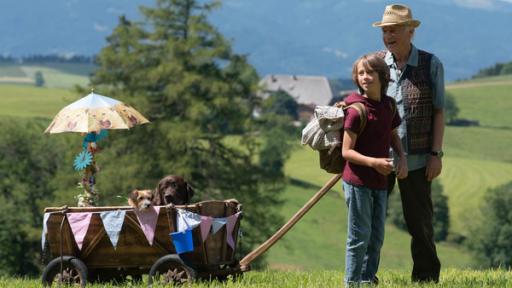 Ein Junge zieht mit seinem Opa einen Bollerwagen in dem zwei Hunde sitzen