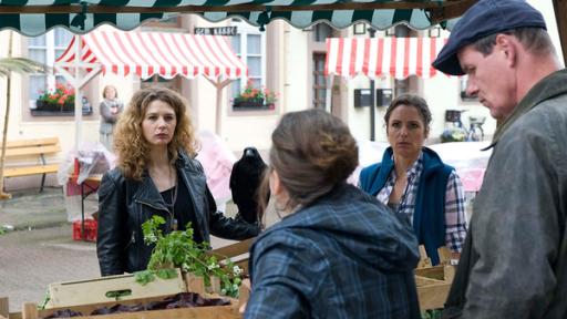 mehrere Personen unterhalten sich an einem Marktstand