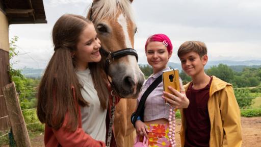 Zwei Mädchen und ein Junge machen ein Selfie mit Pferd