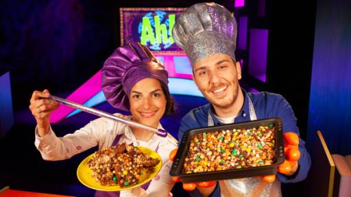 Clarissa und Tarkan präsentieren Essen in funkelnden Kochmützen