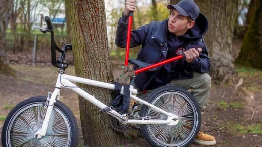 Ein Junge knackt mit einer großen Zange ein Fahrradschloss